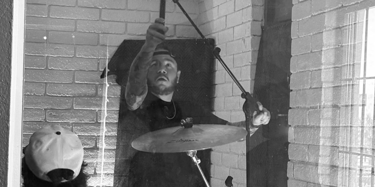 GoatHead Audio engineer positioning an overhead microphone above a cymbal during session setup
