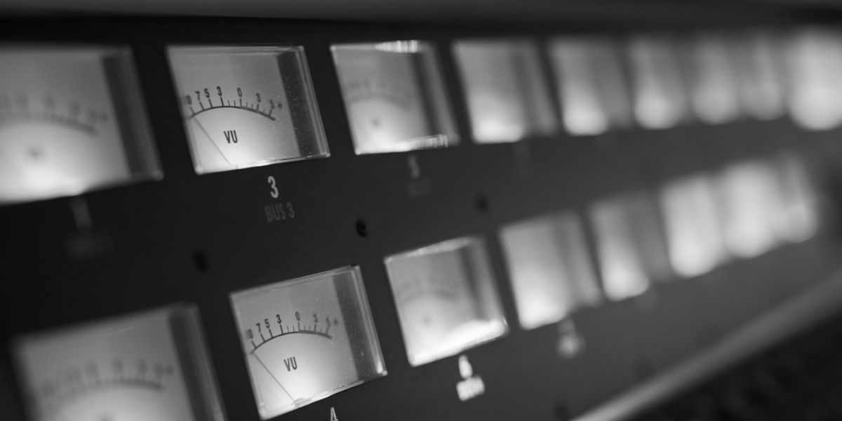Black and white close-up of illuminated VU meters on rack-mounted bus compressor